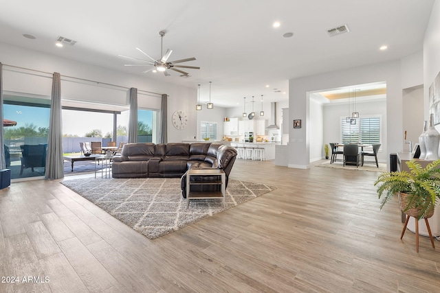 living room with a wealth of natural light, ceiling fan, and light wood-type flooring