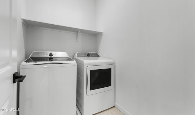 clothes washing area featuring separate washer and dryer and light tile patterned floors