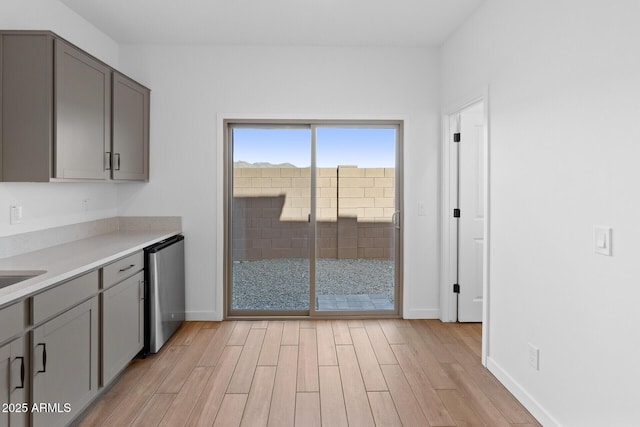 kitchen featuring stainless steel dishwasher, light wood-type flooring, and gray cabinetry