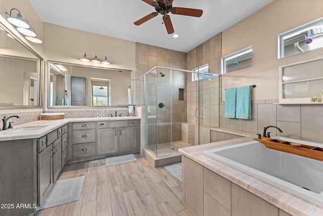 bathroom with hardwood / wood-style flooring, ceiling fan, vanity, and plus walk in shower