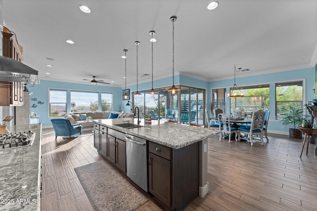 kitchen with light stone counters, stainless steel appliances, sink, and hanging light fixtures