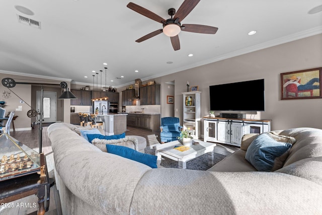 living room with dark hardwood / wood-style flooring, sink, crown molding, and ceiling fan