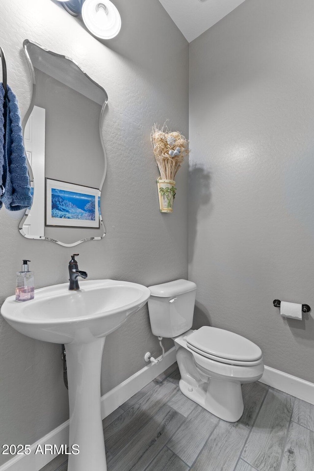 bathroom with toilet, sink, and hardwood / wood-style floors