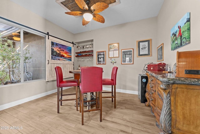 dining room featuring a barn door, plenty of natural light, light wood-type flooring, and ceiling fan