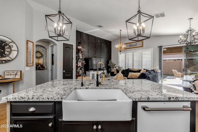 kitchen featuring arched walkways, a sink, visible vents, open floor plan, and an inviting chandelier