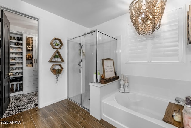 bathroom featuring a shower stall, a chandelier, a bath, and wood finish floors