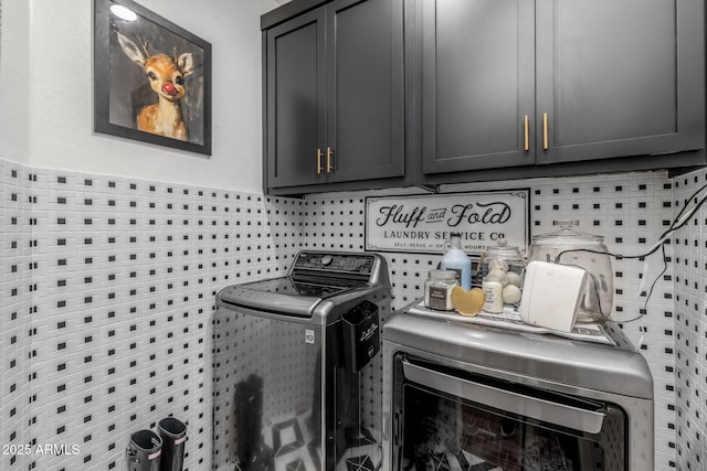 clothes washing area featuring tile walls, cabinet space, and washer and clothes dryer