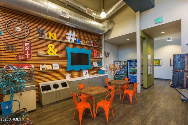 game room with a towering ceiling, visible vents, and wood finished floors