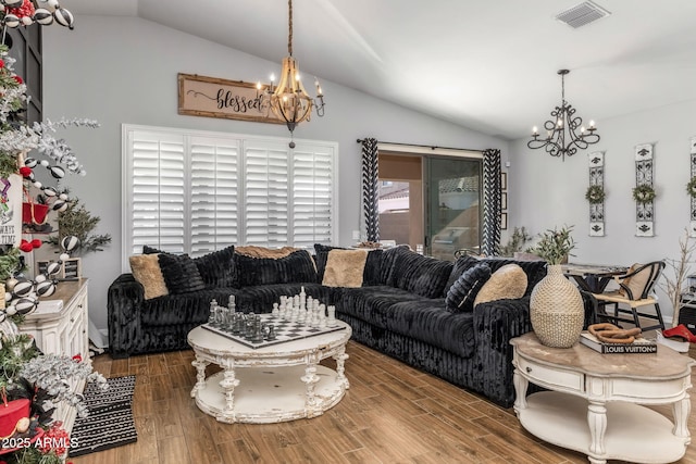 living room featuring a chandelier, vaulted ceiling, wood finished floors, and visible vents