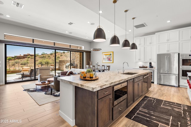 16134 E Ridgestone Dr, Fountain Hills, AZ 85268 - kitchen with stainless steel appliances, white cabinets, dark brown cabinetry, light wood-style floors, and recessed lighting
