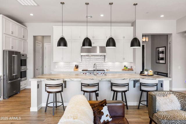16134 E Ridgestone Dr, Fountain Hills, AZ 85268 - kitchen with stainless steel appliances, wall chimney exhaust hood, light wood finished floors, white cabinetry, and backsplash