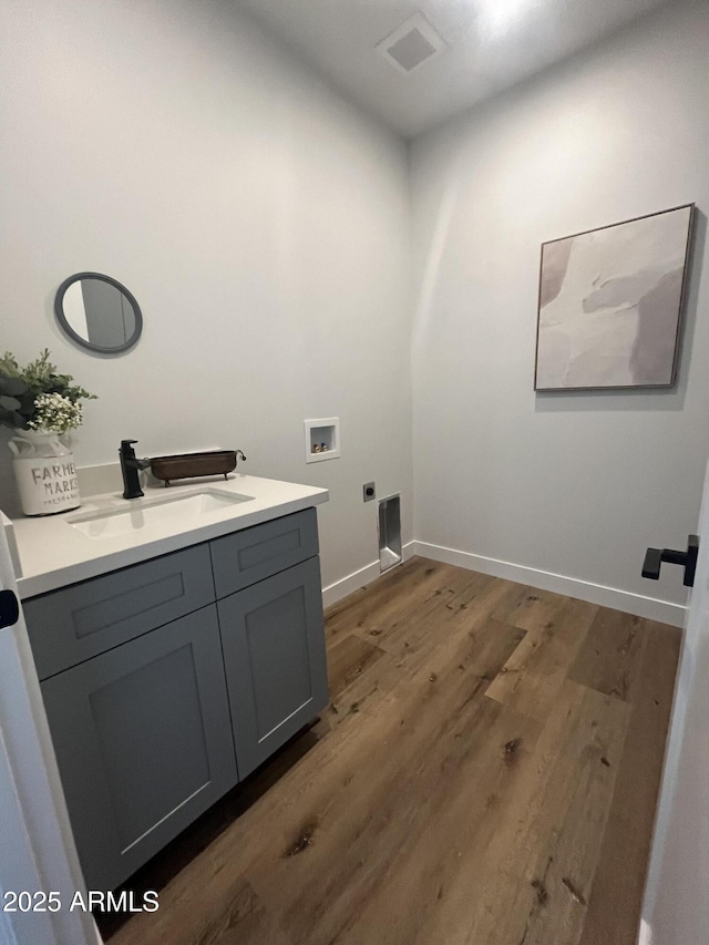 washroom with dark hardwood / wood-style floors, sink, cabinets, washer hookup, and electric dryer hookup