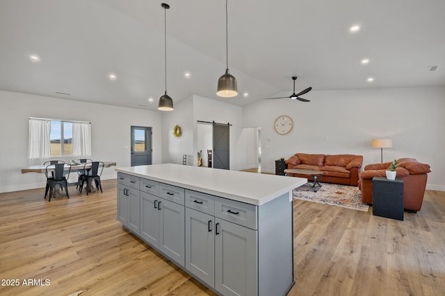 kitchen with gray cabinetry, hanging light fixtures, a barn door, and a kitchen island