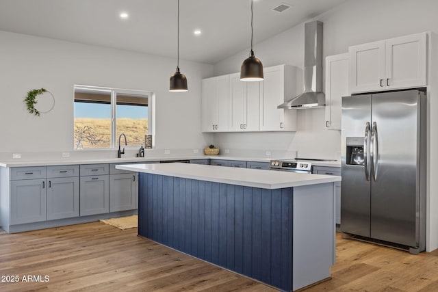 kitchen with wall chimney exhaust hood, pendant lighting, appliances with stainless steel finishes, and white cabinets