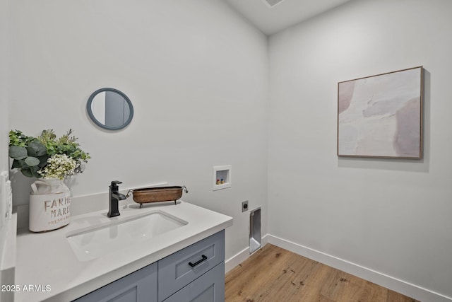 laundry room with sink, cabinets, hookup for a washing machine, hookup for an electric dryer, and light hardwood / wood-style flooring