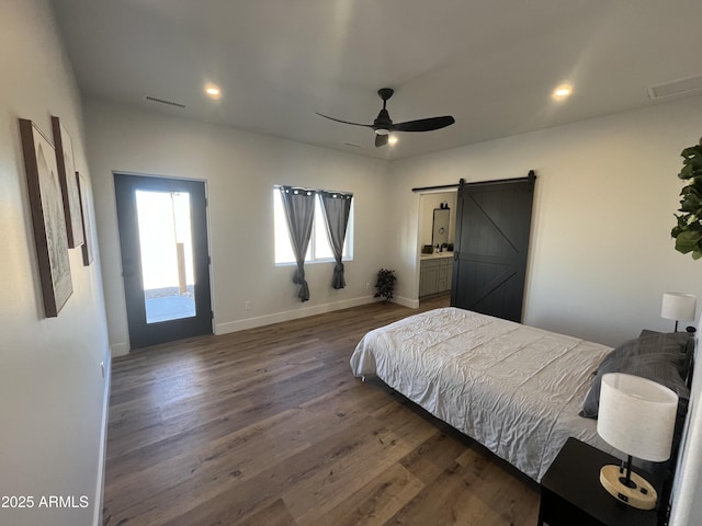 bedroom with dark wood-type flooring, ceiling fan, and a barn door