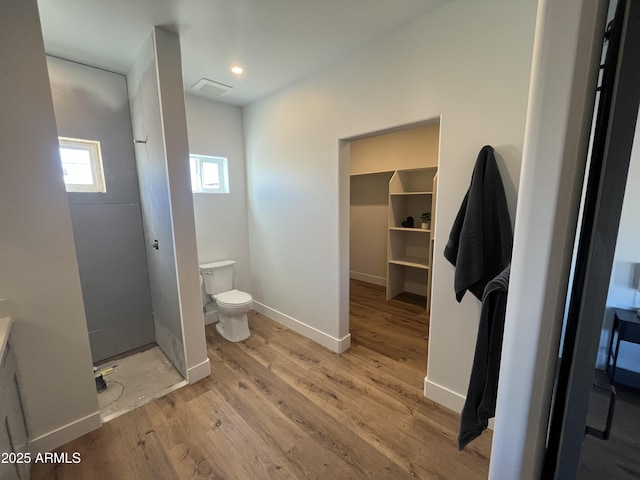 bathroom featuring walk in shower, hardwood / wood-style floors, and toilet