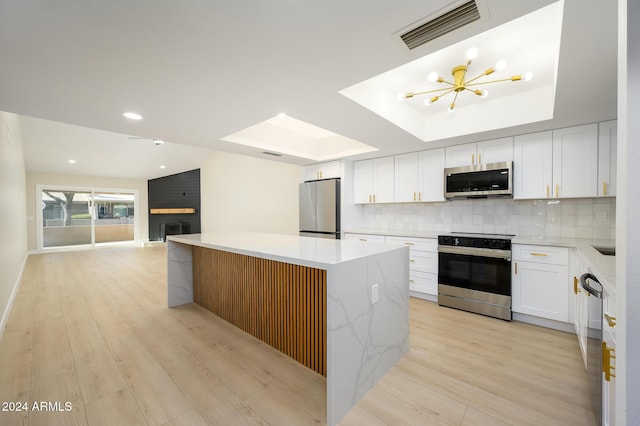 kitchen featuring white cabinets, a kitchen island, light wood-type flooring, and stainless steel appliances