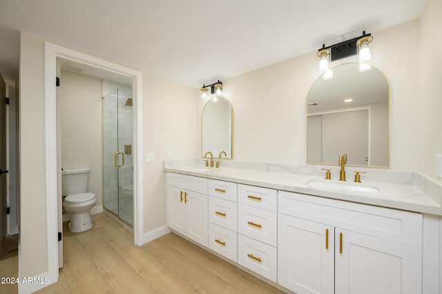 bathroom featuring hardwood / wood-style flooring, toilet, vanity, and an enclosed shower