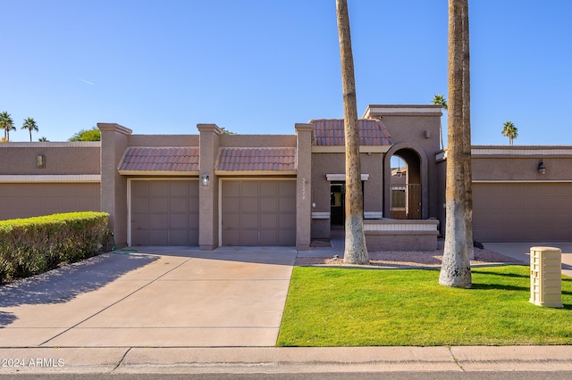 pueblo-style house with a garage and a front lawn