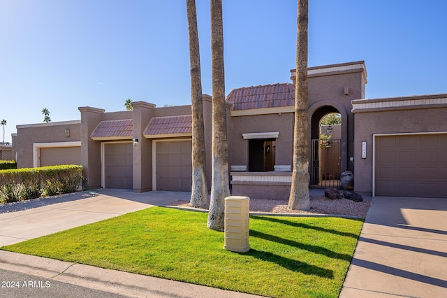 mediterranean / spanish-style home with a garage and a front lawn