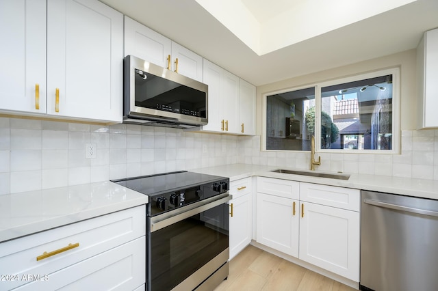 kitchen featuring sink, stainless steel appliances, white cabinets, and light hardwood / wood-style floors