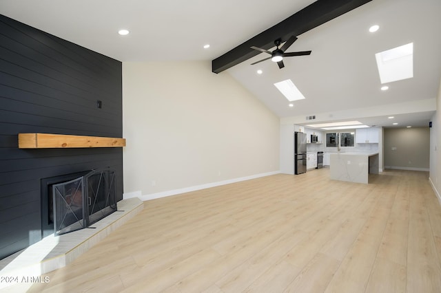 unfurnished living room with a tile fireplace, light hardwood / wood-style floors, ceiling fan, and lofted ceiling with skylight