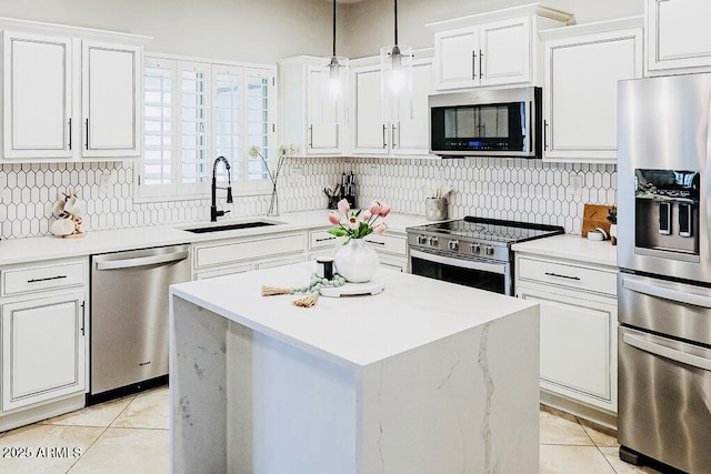 kitchen with sink, white cabinets, hanging light fixtures, a center island, and stainless steel appliances