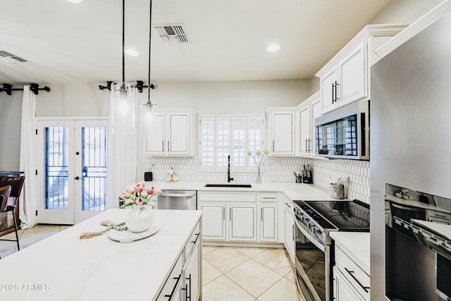 kitchen featuring white cabinetry, sink, hanging light fixtures, and appliances with stainless steel finishes