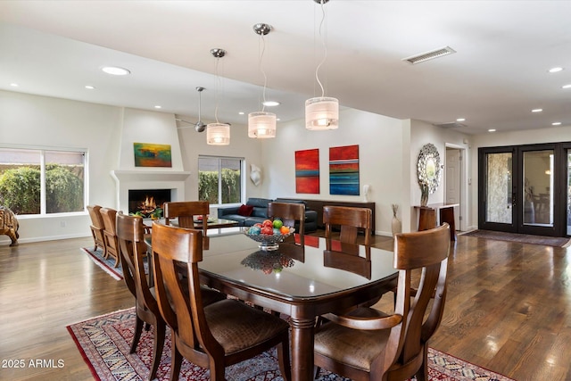 dining room featuring dark wood-type flooring, a large fireplace, and a wealth of natural light