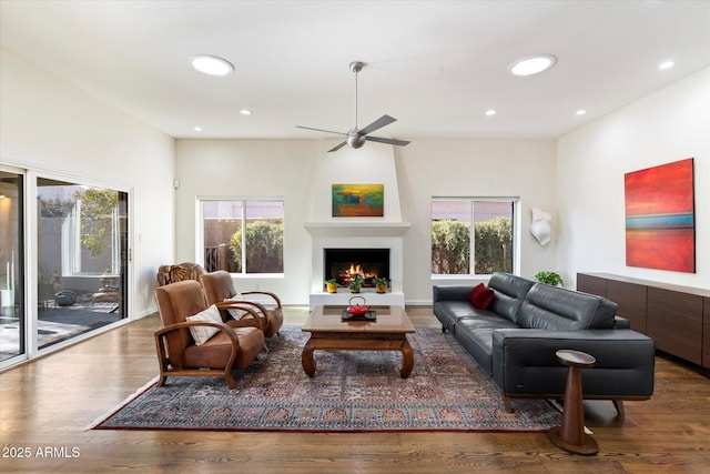 living room with ceiling fan, wood-type flooring, a fireplace, and plenty of natural light