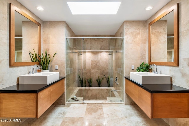 bathroom featuring vanity, a skylight, tile walls, and a shower with door