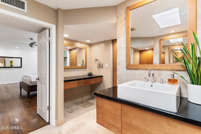 bathroom with a skylight, hardwood / wood-style flooring, and vanity