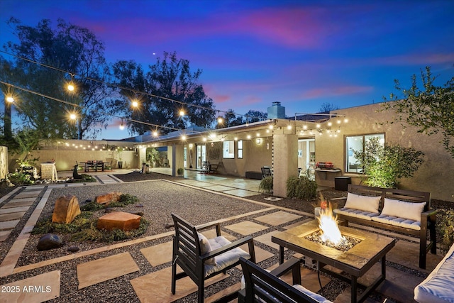 back house at dusk with a patio area and an outdoor fire pit