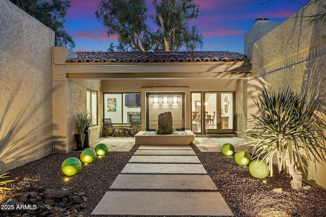 exterior entry at dusk featuring a patio