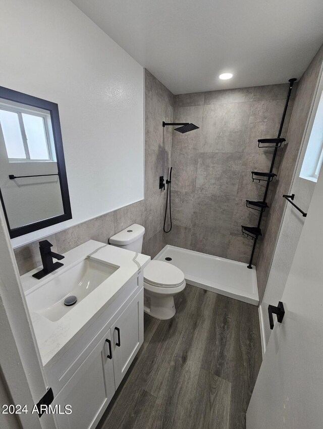 full bathroom featuring hardwood / wood-style floors, vanity, tiled shower / bath combo, and toilet