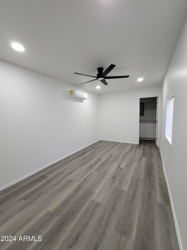 unfurnished room featuring ceiling fan, a wall mounted air conditioner, and hardwood / wood-style flooring