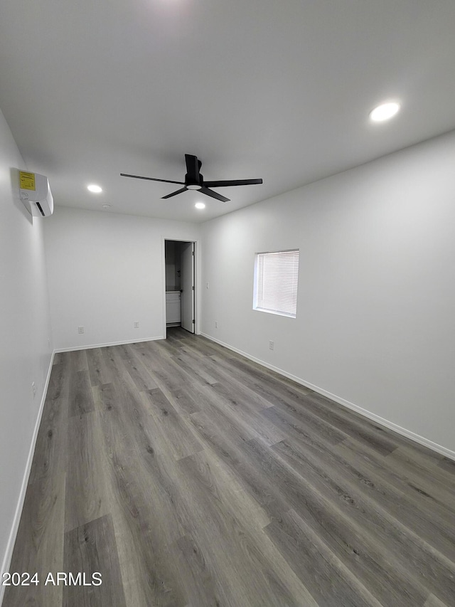 empty room with a wall mounted air conditioner, ceiling fan, and wood-type flooring