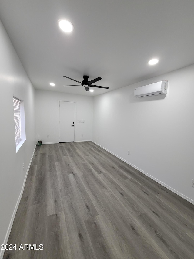 unfurnished room featuring a wall mounted AC, ceiling fan, and wood-type flooring