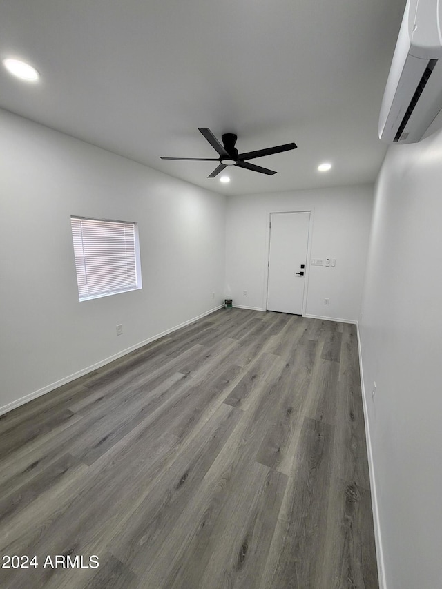 spare room featuring a wall mounted air conditioner, ceiling fan, and hardwood / wood-style floors