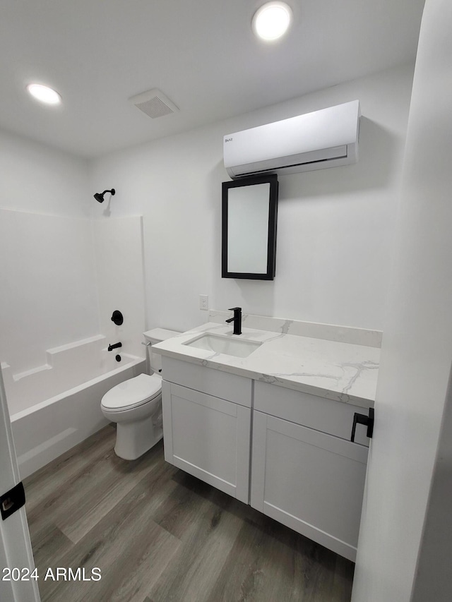 full bathroom with bathtub / shower combination, vanity, an AC wall unit, hardwood / wood-style floors, and toilet