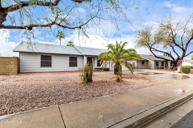 ranch-style house with driveway, a shingled roof, and fence