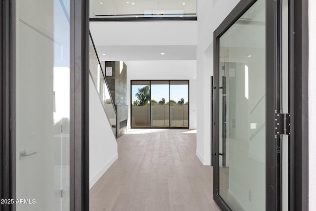 corridor with a towering ceiling and light wood-type flooring