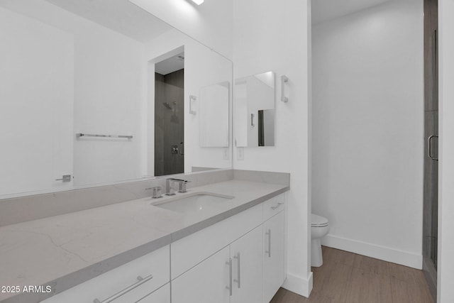 bathroom featuring toilet, an enclosed shower, vanity, and hardwood / wood-style floors