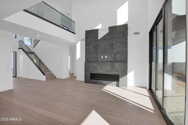 unfurnished living room featuring light hardwood / wood-style floors, a towering ceiling, and a fireplace