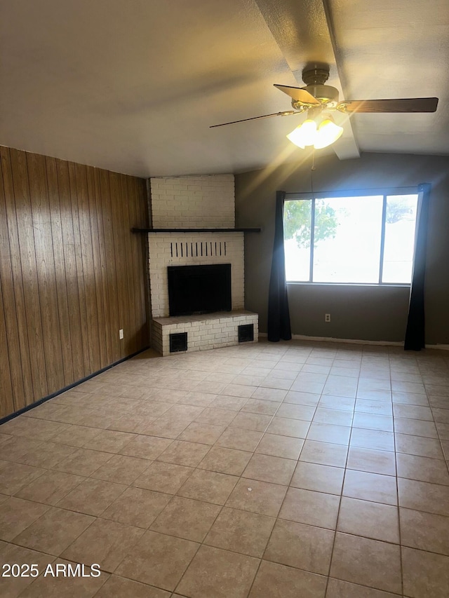 unfurnished living room with light tile patterned floors, visible vents, a ceiling fan, a brick fireplace, and wood walls