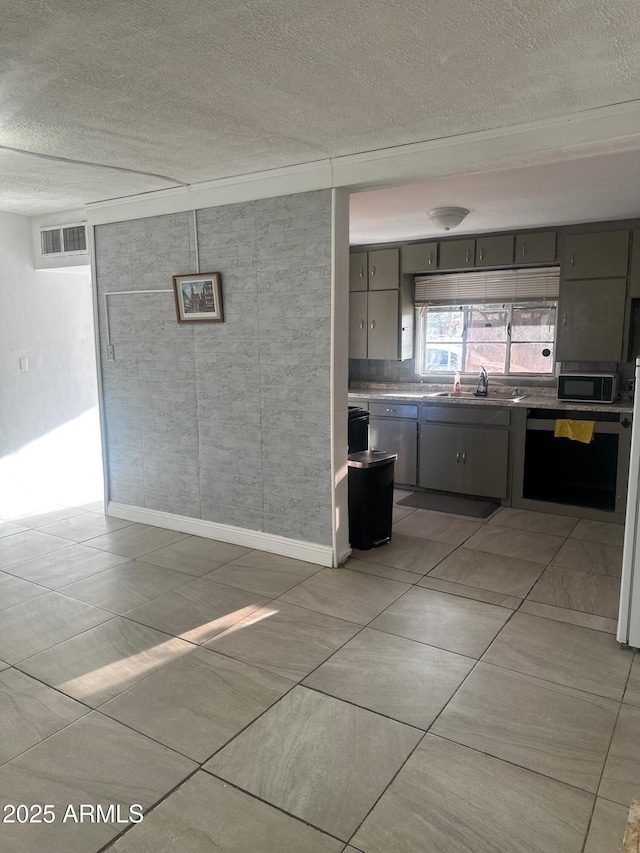 kitchen with black microwave, a textured ceiling, visible vents, and a sink