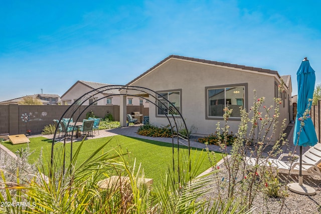 rear view of property featuring a patio and a lawn