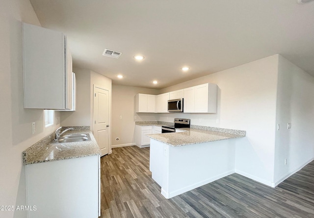 kitchen with visible vents, appliances with stainless steel finishes, white cabinetry, a sink, and a peninsula