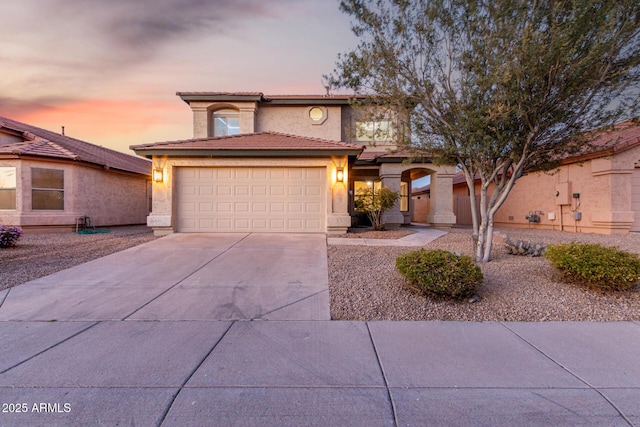 view of front of home featuring a garage, concrete driveway, a tiled roof, and stucco siding